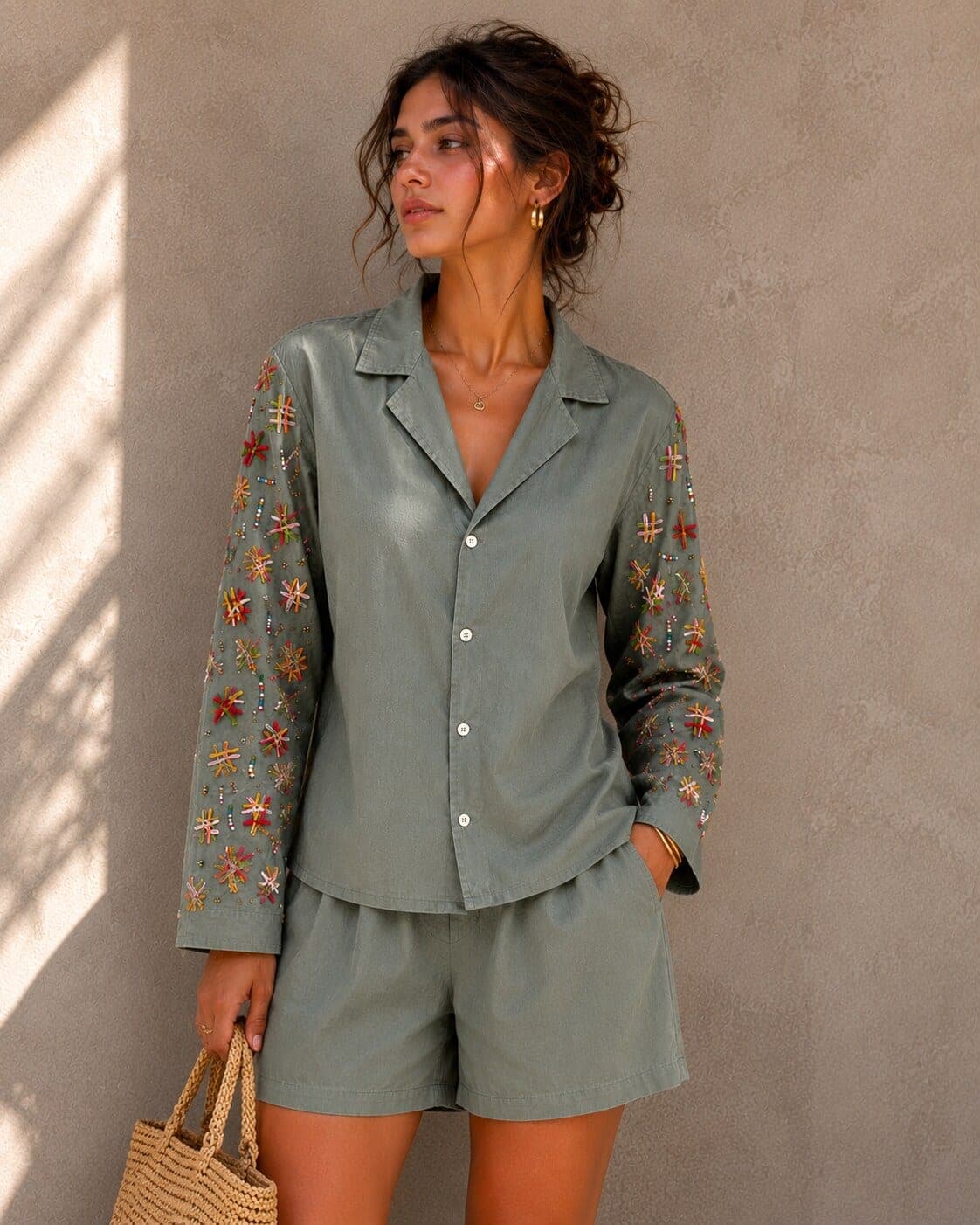 Close view of the shirt worn with matching shorts; woven star motifs and small beads fill the sleeve from shoulder to cuff.