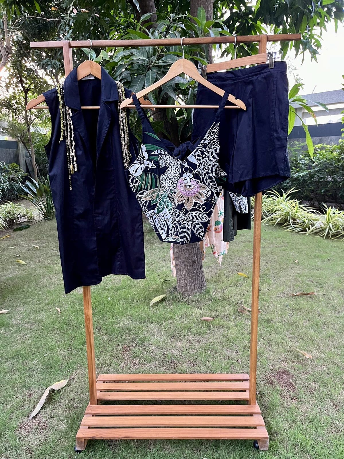 Black set laid out on the rail: sleeveless blazer, embroidered leopard-and-passion-flower top, and matching shorts clipped to a hanger behind.