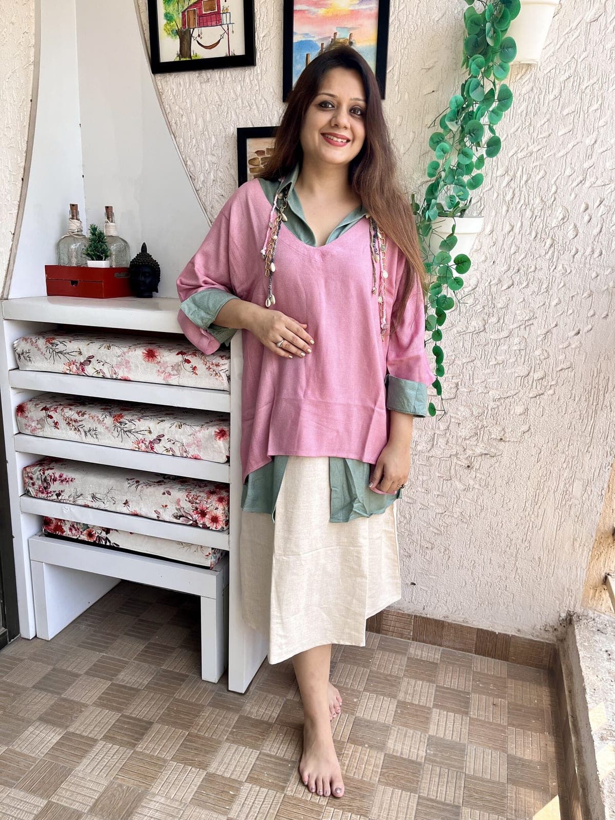 Dusty pink tunic layered over a sage green collared shirt and ivory slip, tasselled shell ties hanging from the V-neck.