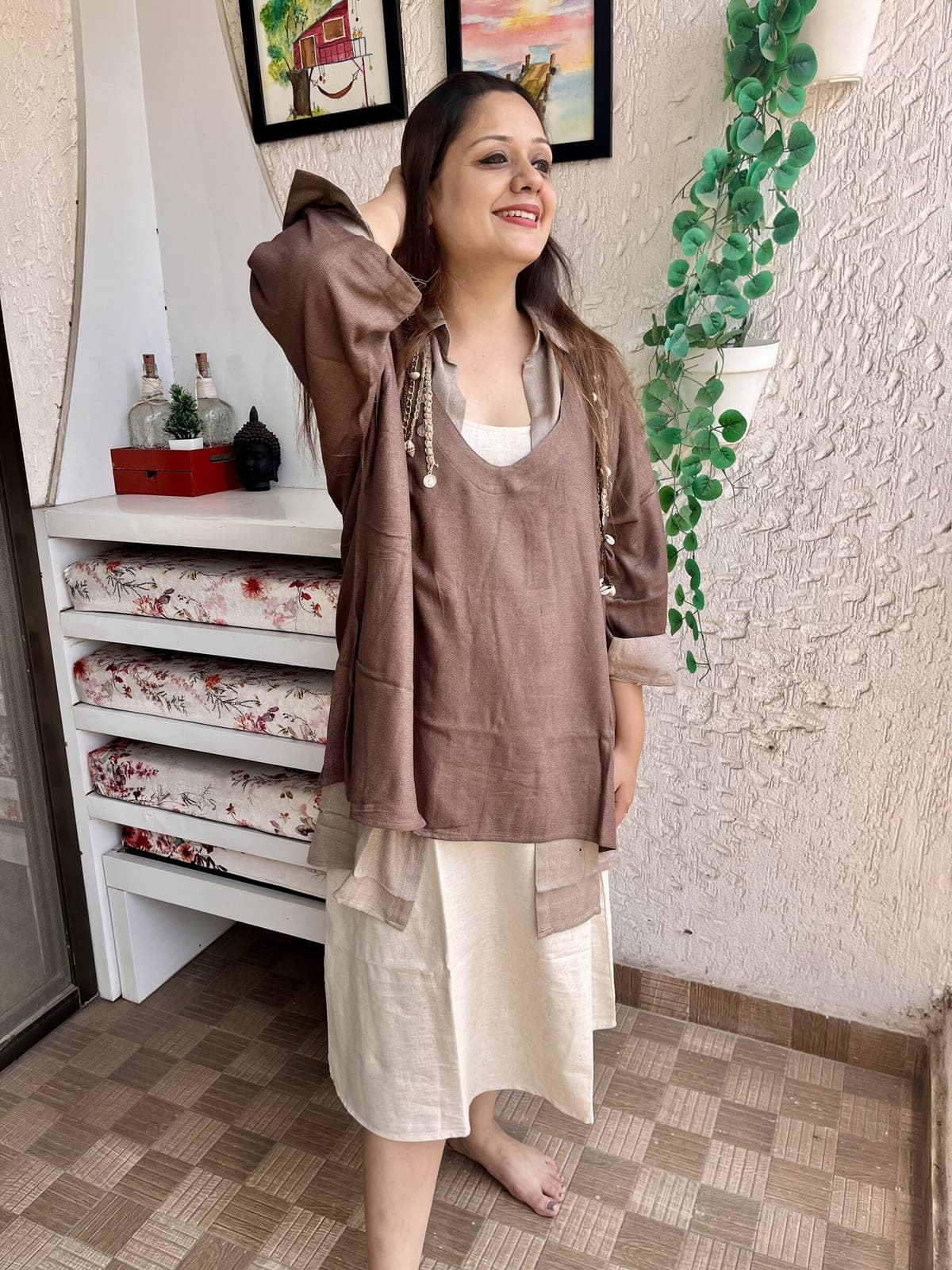 Mocha brown tunic over a taupe collared shirt and the ivory slip dress, one arm raised, cuffs turned back.