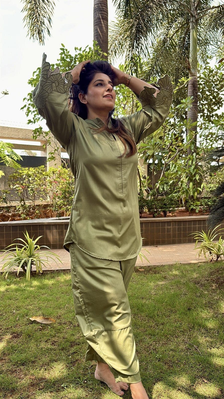 Olive green viscose-blend kurta and tapered trousers on a model, arms raised to show the scalloped cutwork petal at either sleeve.