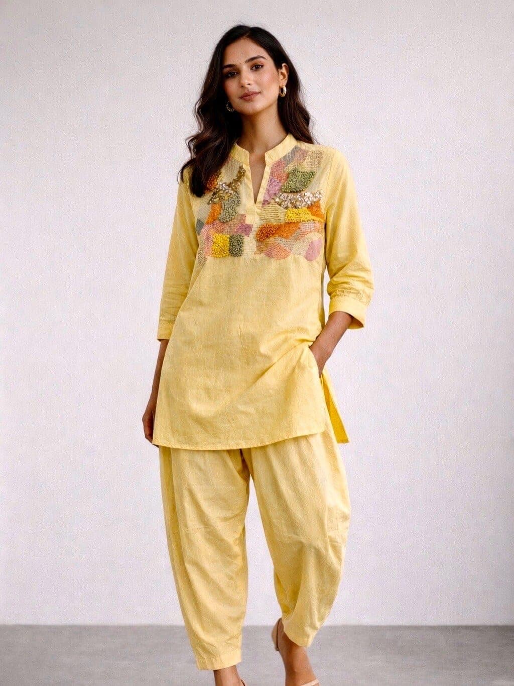 Soft yellow cotton kurta and gathered pathani-style trousers, a patchwork panel in pastel shades running across the chest and shoulder.