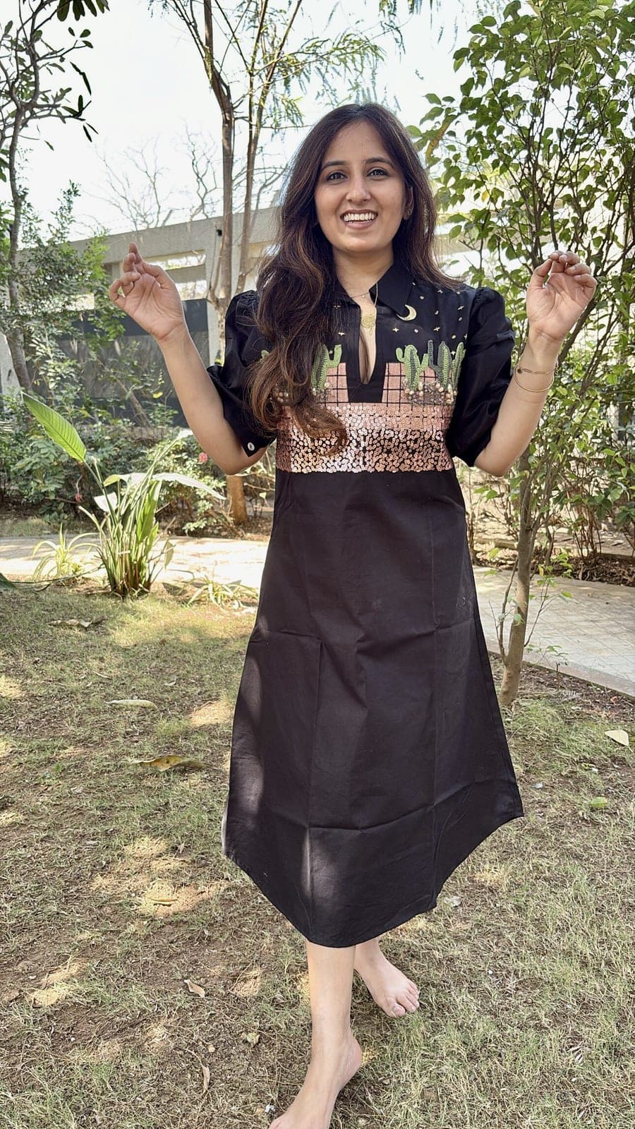 Black cotton dress worn in a garden, green cactus embroidery and copper sequins banding the chest above a plain A-line skirt.