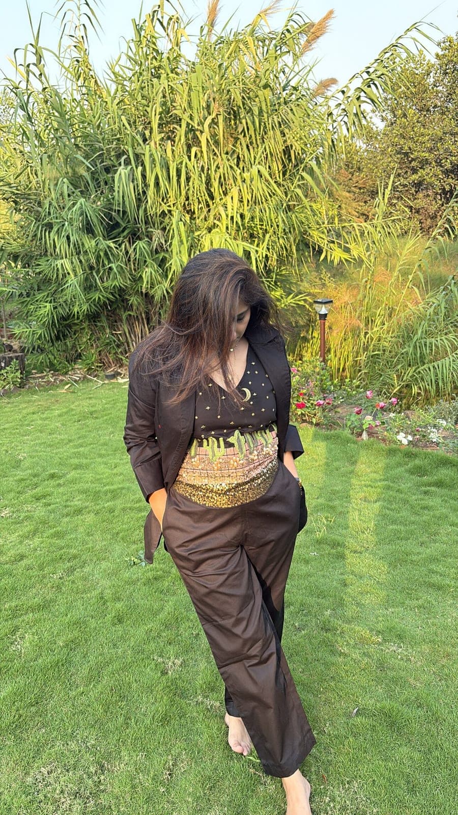 Wide-leg black pants replace the shorts here, worn with the blazer and embroidered top, gold sequin band catching low sun.